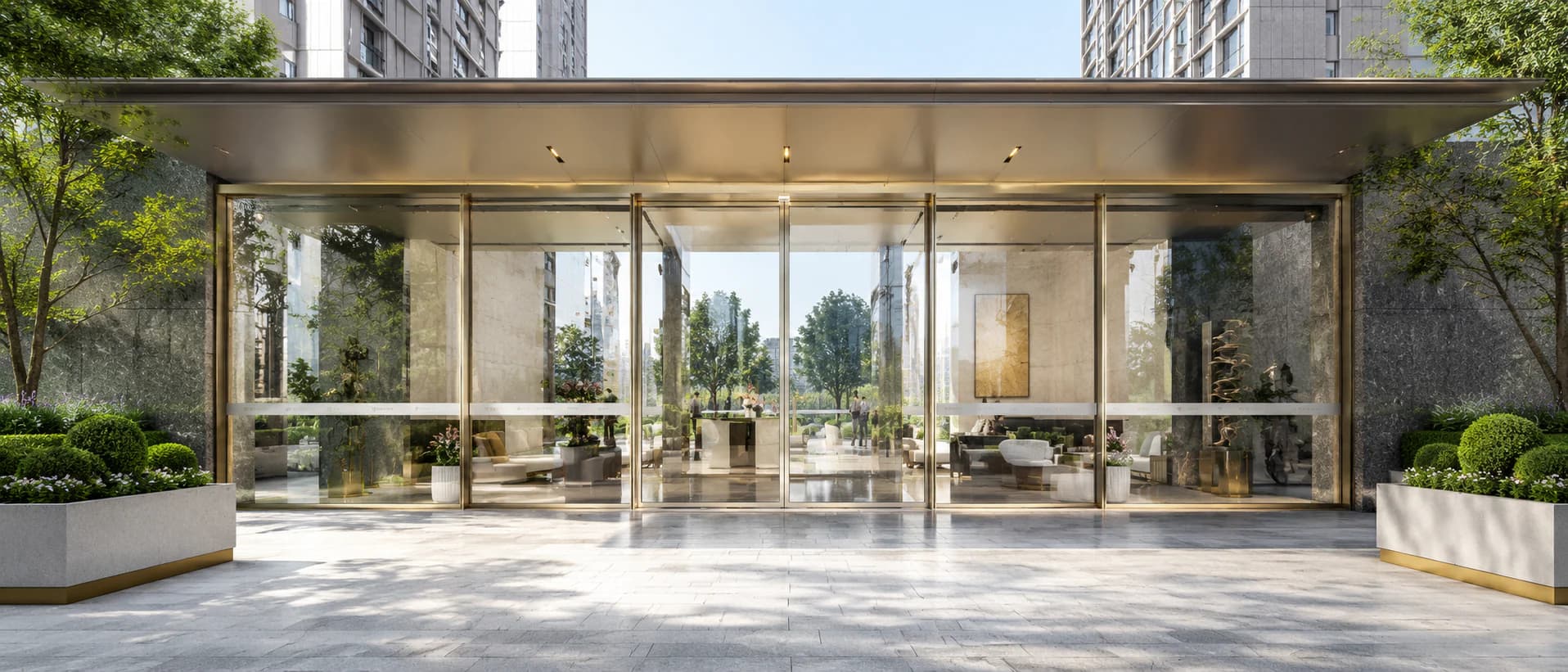 Wide commercial automatic sliding glass doors beneath a landscaped building entrance canopy